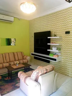 a living room with two couches and a flat screen tv at CEMPAKA IRIS HOMESTAY in Kampung Bota Kiri