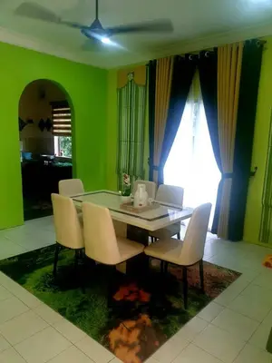 a dining room with a table and chairs and green walls at CEMPAKA IRIS HOMESTAY in Kampung Bota Kiri