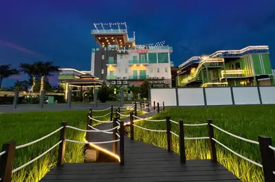 a wooden boardwalk leading up to a building at night at Villa Chee in Sekincan