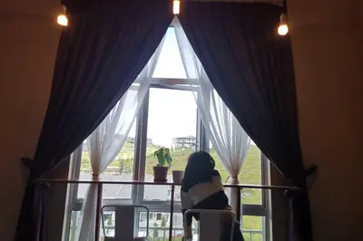 a woman sitting in a chair looking out of a window at LOVE LODGE BRINCHANG, CAMERON HIGHLANDS in Tanah Rata