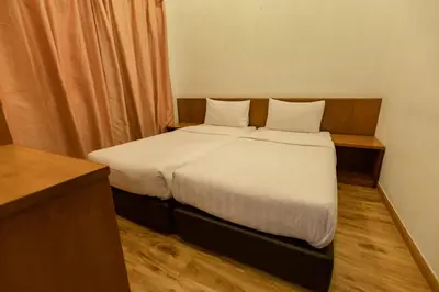 a small bedroom with a bed with white sheets at Hills Aranda Nova Hotel in Cameron Highlands