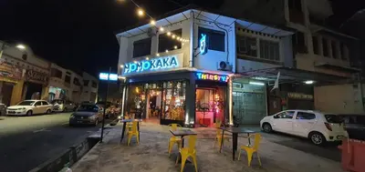 a building with tables and yellow chairs on a street at night at Room at Lebuh Armenian Georgetown City Center in George Town