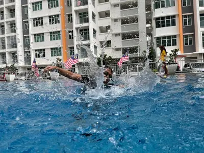 a boy is playing in a fountain in a swimming pool at HOMESTAY NazIPOH Meru in Ipoh