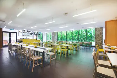 a dining room with tables and yellow chairs at MU Hotel in Ipoh