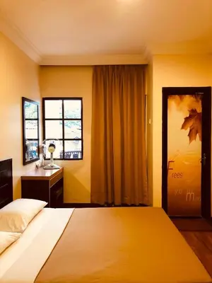 a bedroom with a bed and a desk and a window at Hotel Chua Gin @ Brinchang Centre in Brinchang