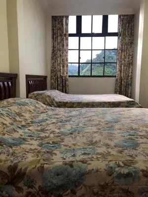 two beds in a bedroom with a large window at Hotel Chua Gin @ Brinchang Centre in Brinchang