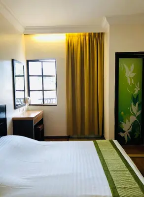 a bedroom with a bed and a desk and a window at Hotel Chua Gin @ Brinchang Centre in Brinchang
