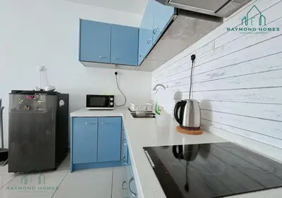 a kitchen with blue cabinets and a refrigerator at Gurney Drive Mansion One Serviced Apartment in George Town