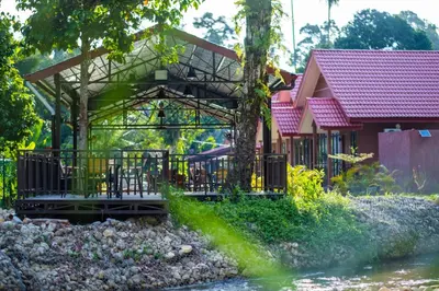 a house with a bridge next to a river at Cinta Abadi Resort in Bidur