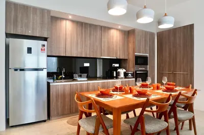 a kitchen with a table with chairs and a refrigerator at Beachfront Resort By The Sea, Batu Ferringhi in Batu Ferringhi