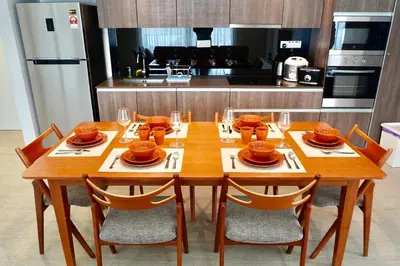 a wooden table with chairs and plates and wine glasses at Beachfront Resort By The Sea, Batu Ferringhi in Batu Ferringhi