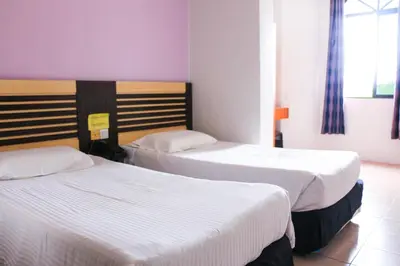two beds in a hotel room with white sheets at Hotel Lam Seng in Pantai Remis