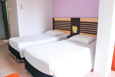 two twin beds in a room with purple walls at Hotel Lam Seng in Pantai Remis