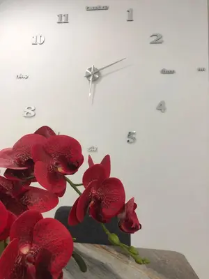 a white clock with red flowers on a table at Ramadhina Eagle Eye View Home2stay Emerald Avenue in Brinchang