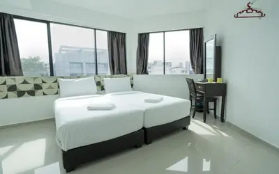 a bedroom with a bed and a table and windows at Grand Bagan Hotel in Butterworth