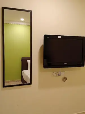 a flat screen tv on a wall next to a mirror at HOTEL SAHARA INN TANJUNG MALIM in Kampong Chabang
