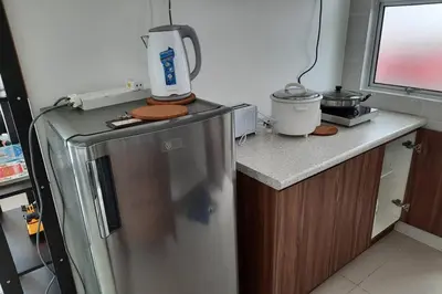 a kitchen with a refrigerator and a counter top at Lily Homestay Barrington Square Cameron Highlands. in Brinchang