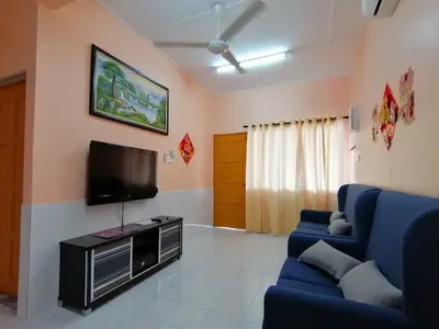 a living room with a blue couch and a tv at Mui Gim Homestay \u5927\u6e2f \u7f8e\u666f\u6c11\u5bbf in Sungai Besar
