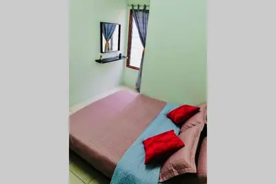 a bedroom with a bed with red pillows on it at LILY VACATION HOME at CAMERON HIGHLANDS - 12 PAX,FREE WiFi w CARPORCH in Tanah Rata
