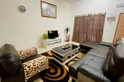 a living room with a leather couch and a television at LILY VACATION HOME at CAMERON HIGHLANDS - 12 PAX,FREE WiFi w CARPORCH in Tanah Rata