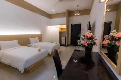 a hotel room with two beds and a table with flowers at Scott Service Suites in George Town