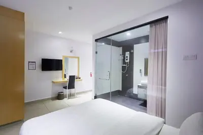 a bedroom with a white bed and a bathroom at East Sun Hotel Sekinchan in Sekincan