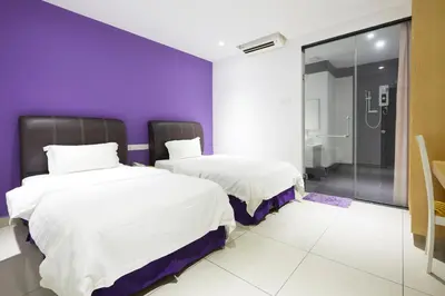 two beds in a room with a purple wall at East Sun Hotel Sekinchan in Sekincan