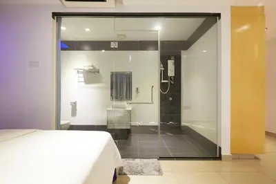 a glass shower in a bedroom with a bed at East Sun Hotel Sekinchan in Sekincan