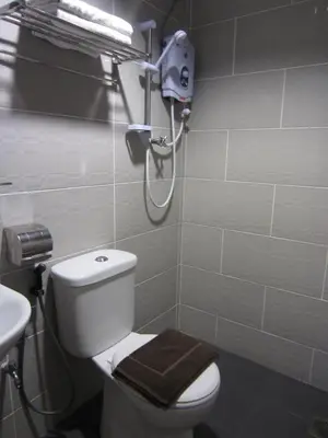 a bathroom with a toilet with a brown towel on it at Radiant Hotel in Sitiawan