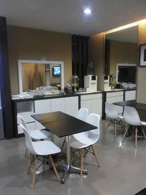a kitchen with two tables and white chairs and a counter at Radiant Hotel in Sitiawan