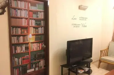 a living room with a tv and a book shelf with books at Tambun homestay in Ipoh