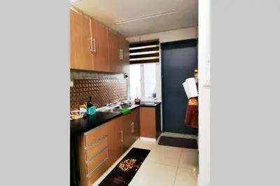 a kitchen with wooden cabinets and a black counter top at Bintang Maya Residence cozy and comfortable stay in Sungai Petani