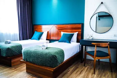 a bedroom with two beds and a mirror and a desk at The Journey hotel in George Town