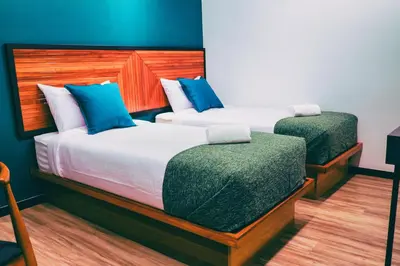 two beds in a room with blue walls and wood at The Journey hotel in George Town
