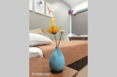 a blue vase with flowers on a table next to a bed at PANGKOR 66’s HOME in Kampong Sungai Udang