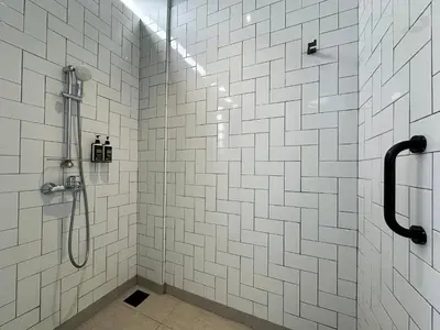 a bathroom with a shower with white tiles at Ten Mentigi in Tanah Rata