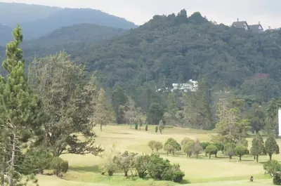 a golf course with trees and mountains in the background at CH Green Stay Resort Apartment in Cameron Highlands