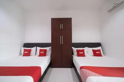 two beds with red pillows in a room at Guesthouse Fasa 2B in Seri Manjung