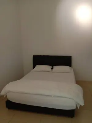 a bed with white sheets and a black headboard in a room at Zarena Somersquare Goldenhills Pasar Malam Tanah Rata Cameron Highlands in Tanah Rata