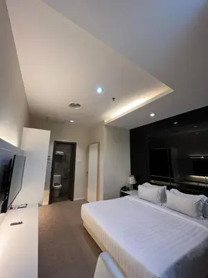 a bedroom with a large white bed and a television at Jindagu Hotel Ipoh in Ipoh