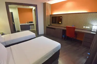 a hotel room with two beds and a desk at Jindagu Hotel Ipoh in Ipoh
