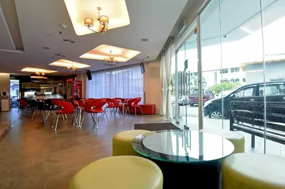 a restaurant with red chairs and tables and windows at Jindagu Hotel Ipoh in Ipoh
