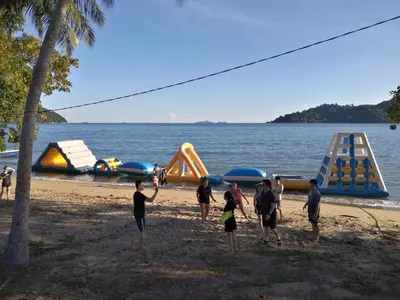 a group of people standing on a beach with play equipment at Pangkor staycation apartment in Pangkor