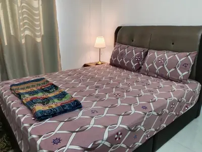 a bed with a pink comforter and pillows on it at Kayu Cengal Homestay in Seri Iskandar