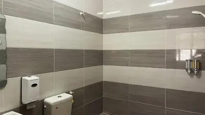 a bathroom with a toilet and a tile wall at Cameron Magpie House in Ringlet