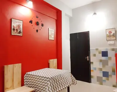 a room with a table and a red wall at G East Ipoh Garden Guesthouse in Ipoh