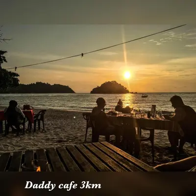a group of people sitting at a table on the beach at Pangkor Coralbay Resort 201 apartment in Pangkor