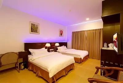 two beds in a hotel room with purple lighting at ERNES Hotel Alma Bukit Mertajam in Bukit Mertajam