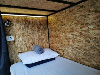 a bed in a room with a stone wall at The Cocoon Capsule Hotel in Cameron Highlands