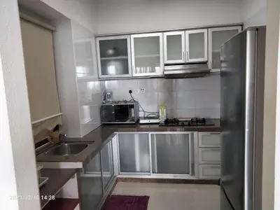 a kitchen with white cabinets and a stainless steel refrigerator at Airbnb at Sri Sayang Batu Ferringhi Beach in Batu Ferringhi